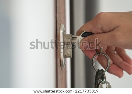Woman using a key to open the lock of the front door