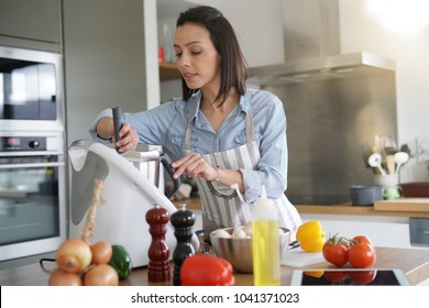 Woman using kitchen robot to prepare dinner