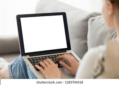 Woman using laptop with blank mock up white empty screen typing on computer at home, mockup copyspace display for ad, job search, study online shopping, website page, e-banking, over shoulder view