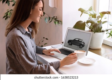 Woman using laptop to buy car at table indoors