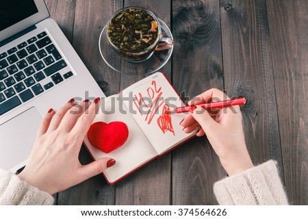 woman using laptop computer and drawing red heart