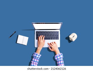 Woman Using A Laptop Computer With A Piggy Bank - Flat Lay