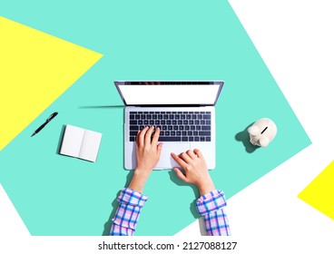 Woman Using A Laptop Computer With A Piggy Bank - Flat Lay