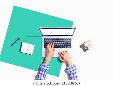 Woman Using A Laptop Computer With A Piggy Bank - Flat Lay