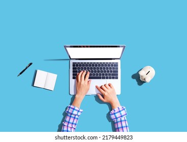 Woman Using A Laptop Computer With A Piggy Bank - Flat Lay