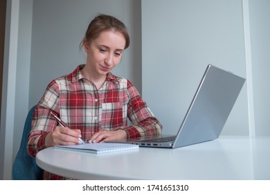 Woman using laptop computer, watching webinar, lecture, making notes in grey room at home. Education, freelance, internet, quarantine, self isolation, learning, technology concept - Powered by Shutterstock