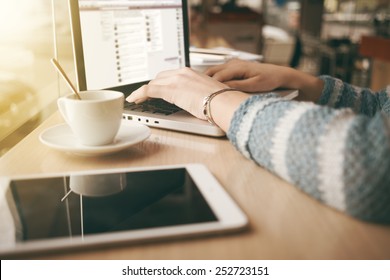 Woman using a laptop during a coffee break, hands close up