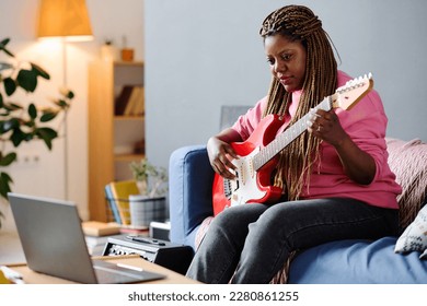 Woman using laptop to learn play guitar - Powered by Shutterstock