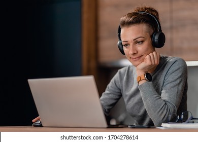 Woman using laptop and listening music at home - Shutterstock ID 1704278614