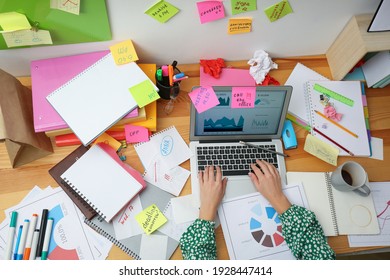Woman using laptop at messy table, top view. Concept of being overwhelmed by work