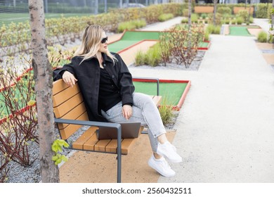 Woman using a laptop and mobile phone on the golf course - Powered by Shutterstock