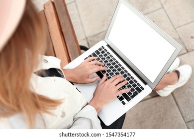 Woman using laptop on bench in city, above view