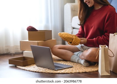 A Woman Using Laptop For Online Shopping , Opening Shopping Bags And Postal Parcel Box At Home