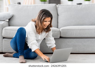 Woman using laptop sitting on the floor of the living room