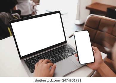 A woman Using Laptop and Smartphone with Blank Screens at a Café Table with Coffee shop. - Powered by Shutterstock