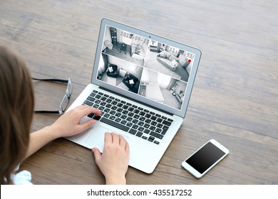 Woman Using Laptop At The Table. Home Security System Concept