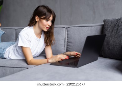 Woman Using A Laptop While Relaxing On The Couch