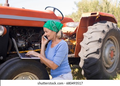 Woman using laptop while talking on mobile phone in olive farm - Powered by Shutterstock