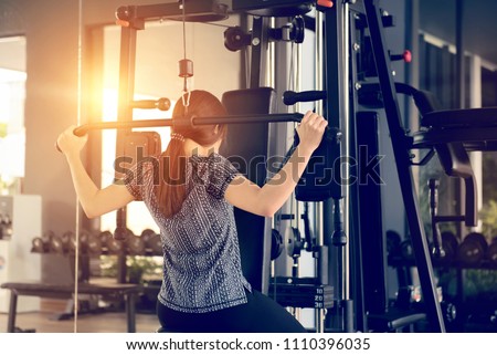 Woman using lat pulldown machine in gym fitness.