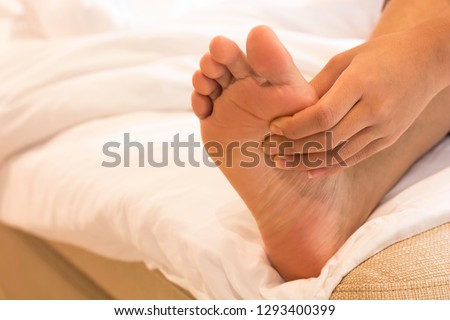 Woman are using the left hand to massage the soles of himself while sitting on a bed in the bedroom. Stock photo © 