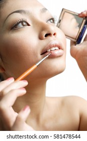 Woman Using Lipstick Brush And Holding Compact Mirror