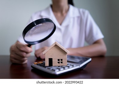 Woman using a magnifying glass to house model and calculator. Searching housing and home insurance concept.  - Shutterstock ID 2022993422