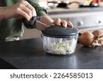 Woman using a manual onion chopper in the kitchen