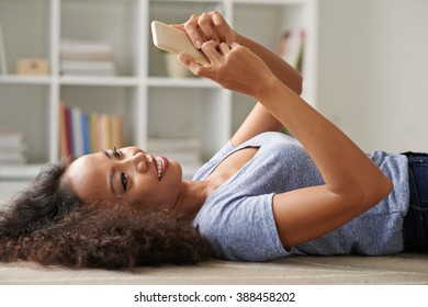 Woman using messenger on her smartphone when lying on the floor