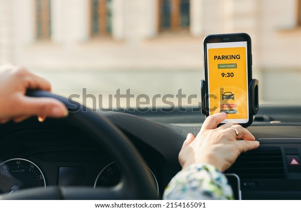 Woman using\
mobile parking app on smartphone. Driver using smartphone to pay\
for parking. Car park application on mobile phone. Convienience\
paying for parking using fast payment\
online