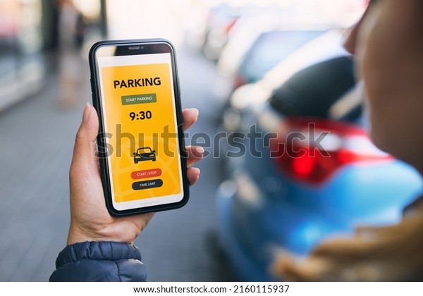 Woman using mobile parking app on smartphone.
Driver using smartphone to pay for parking. Car park application on
mobile phone. Convenience paying for parking using online payment.
Mobile parking