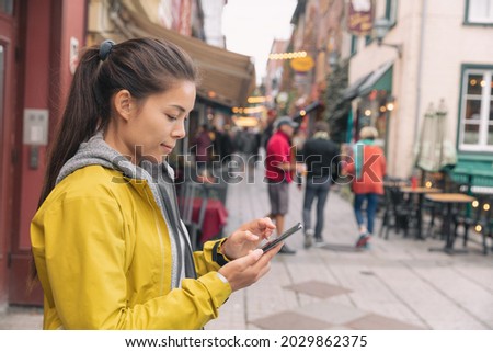 Woman using mobile phone app while walking in city street to find a store direction on map or order online at restaurant. Asian woman canadian city lifestyle.