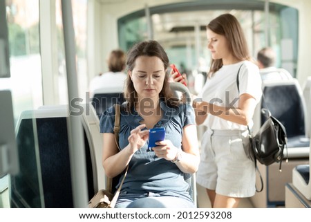 Woman using mobile phone in the cabin of a bus or tram. High quality photo
