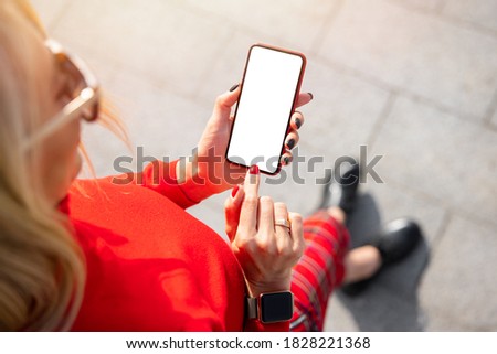 Woman using mobile phone with  empty white mockup screen, view from above