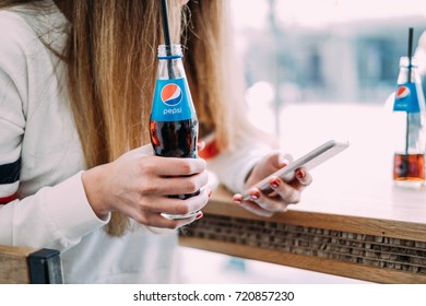 Woman using mobile phone and holding pepsi