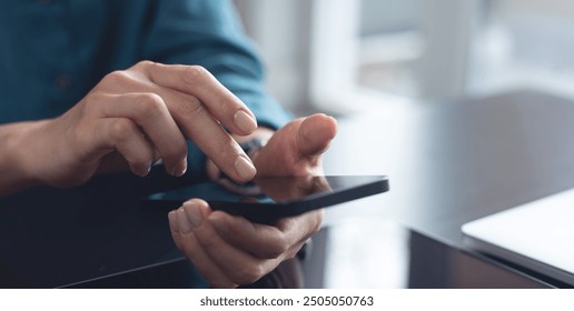 Woman using mobile phone with laptop computer on office table. Business woman surfing the internet, searching the information on smartphone working on laptop computer at workplace - Powered by Shutterstock