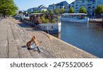 woman using mobile phone and listening music, sitting on stair at city street- Nantes in France