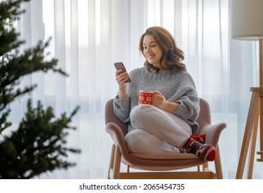 Woman Is Using Mobile Phone In The Living Room Decorated For Christmas.