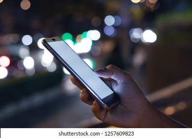Woman using Mobile Phone at night.Abstract night traffic bokeh background.