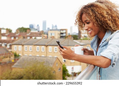 Woman Using Mobile Phone On Rooftop Garden Drinking Coffee - Powered by Shutterstock