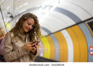 A Woman Using A Mobile Phone On The Tube Underground Station, London