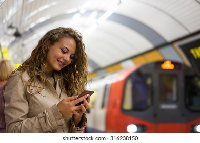 A woman using a mobile phone on the tube underground station, London