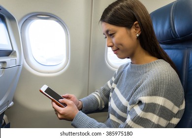 Woman using mobile phone in plane cabin