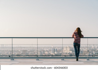 Woman using mobile phone at rooftop during sunset with copy space, communication or lonely people concept.