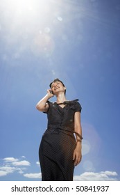 Woman Using Mobile Phone Standing Against Sky, Low Angle View