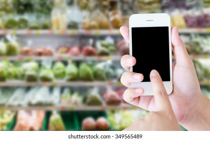 Woman Using Mobile Phone While Shopping In Supermarket, Grocery Store