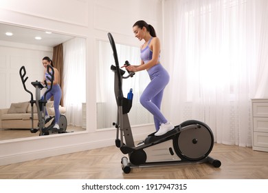 Woman Using Modern Elliptical Machine At Home