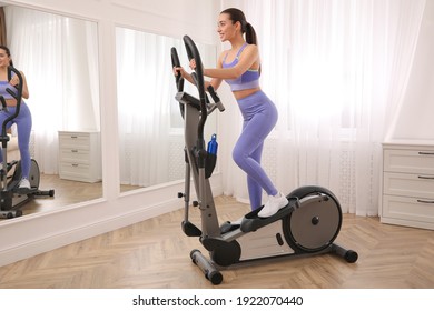 Woman Using Modern Elliptical Machine At Home