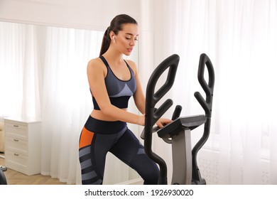 Woman Using Modern Elliptical Machine At Home