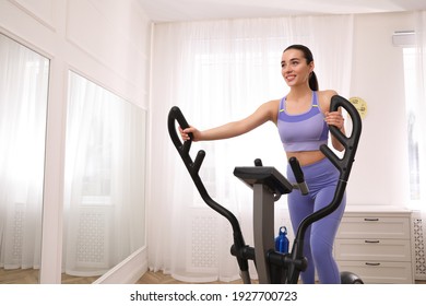 Woman Using Modern Elliptical Machine At Home