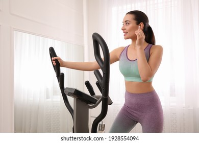 Woman Using Modern Elliptical Machine At Home